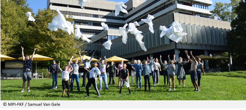 MPI-FKF / Samuel Van Gele A group of students stands on the lawn in front of the MPI-FKF building and joyfully throws white lab coats into the air. Trees and yellow parasols can be seen in the background.
copyright: MPI-FKF / Samuel Van Gele